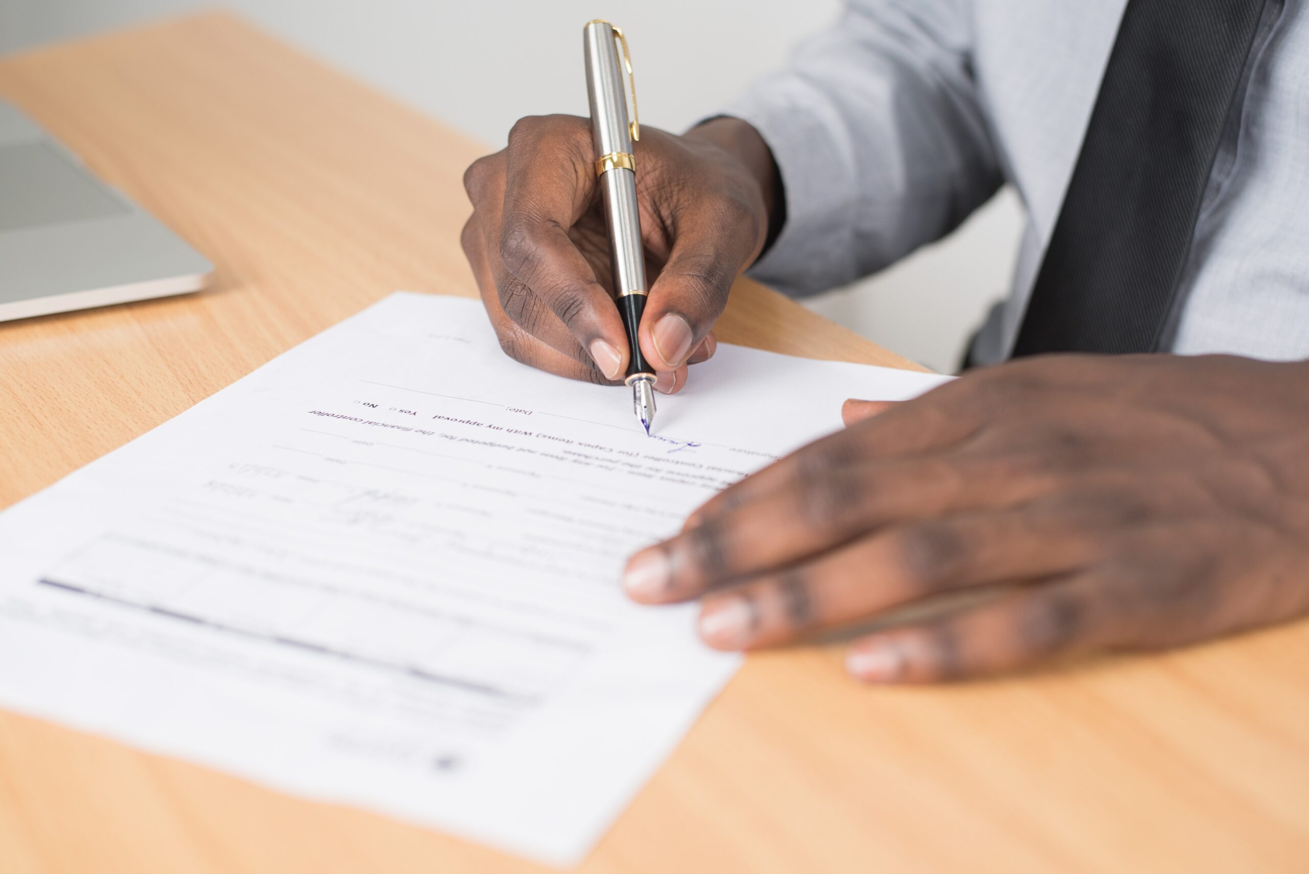 African american man's hands signing document with fountain pen