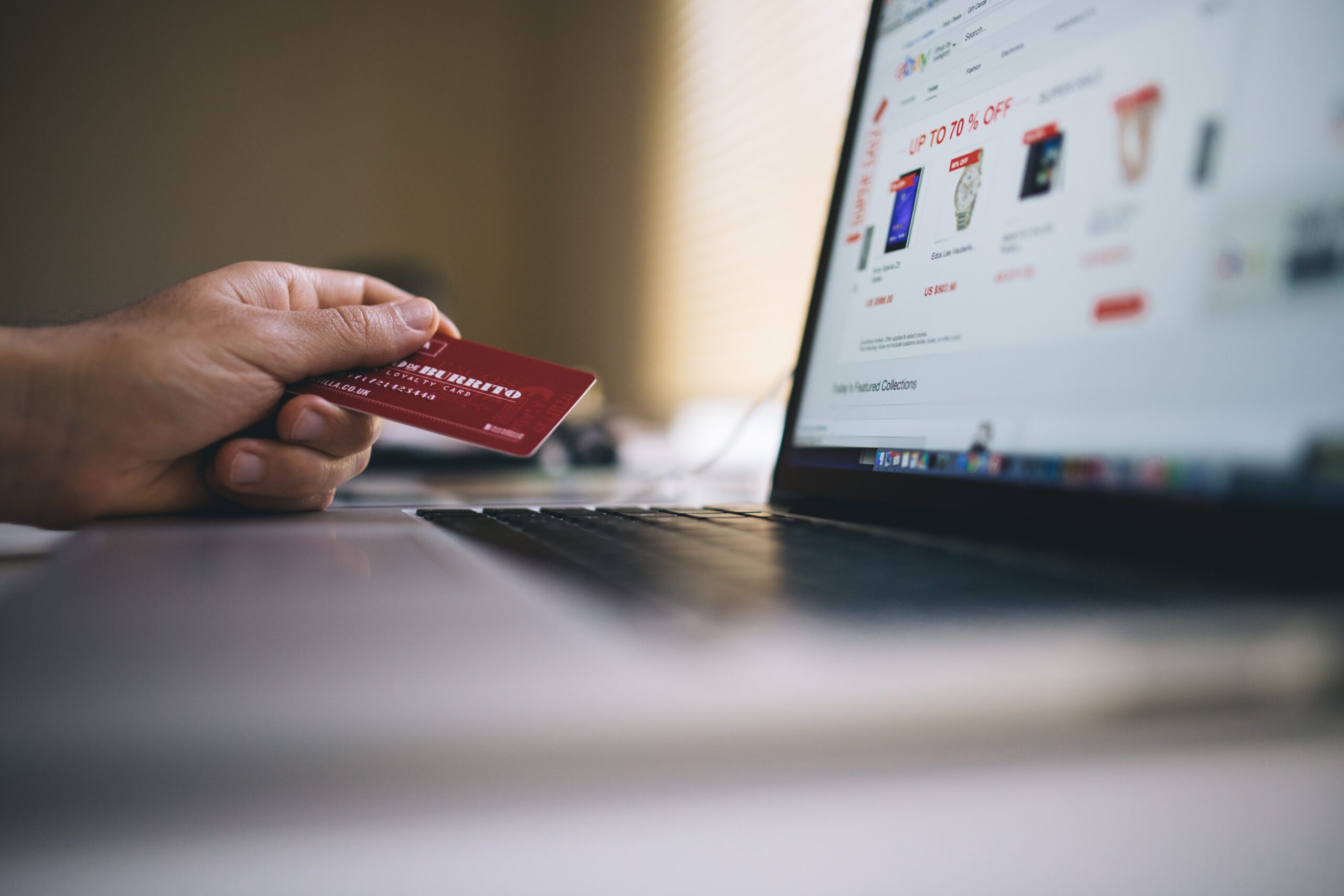 hand holding credit card near laptop while shopping