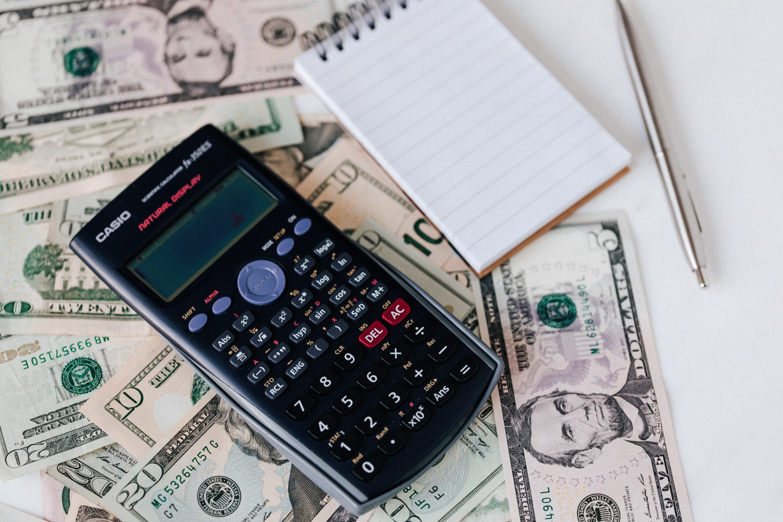 calculator, notepad and pen, with money, dollar bills