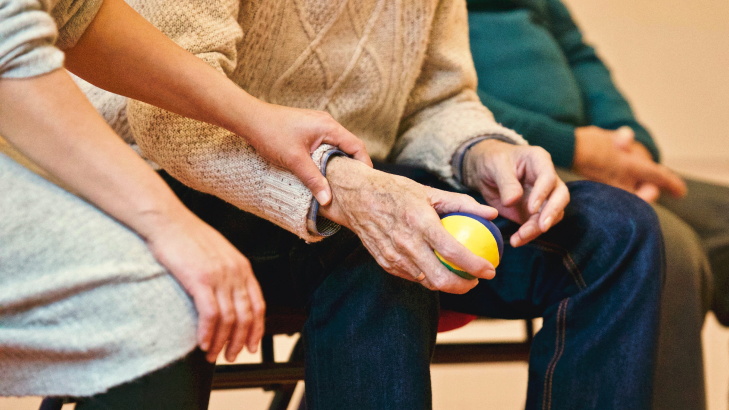 woman hand holding elderly man arm holding a ball