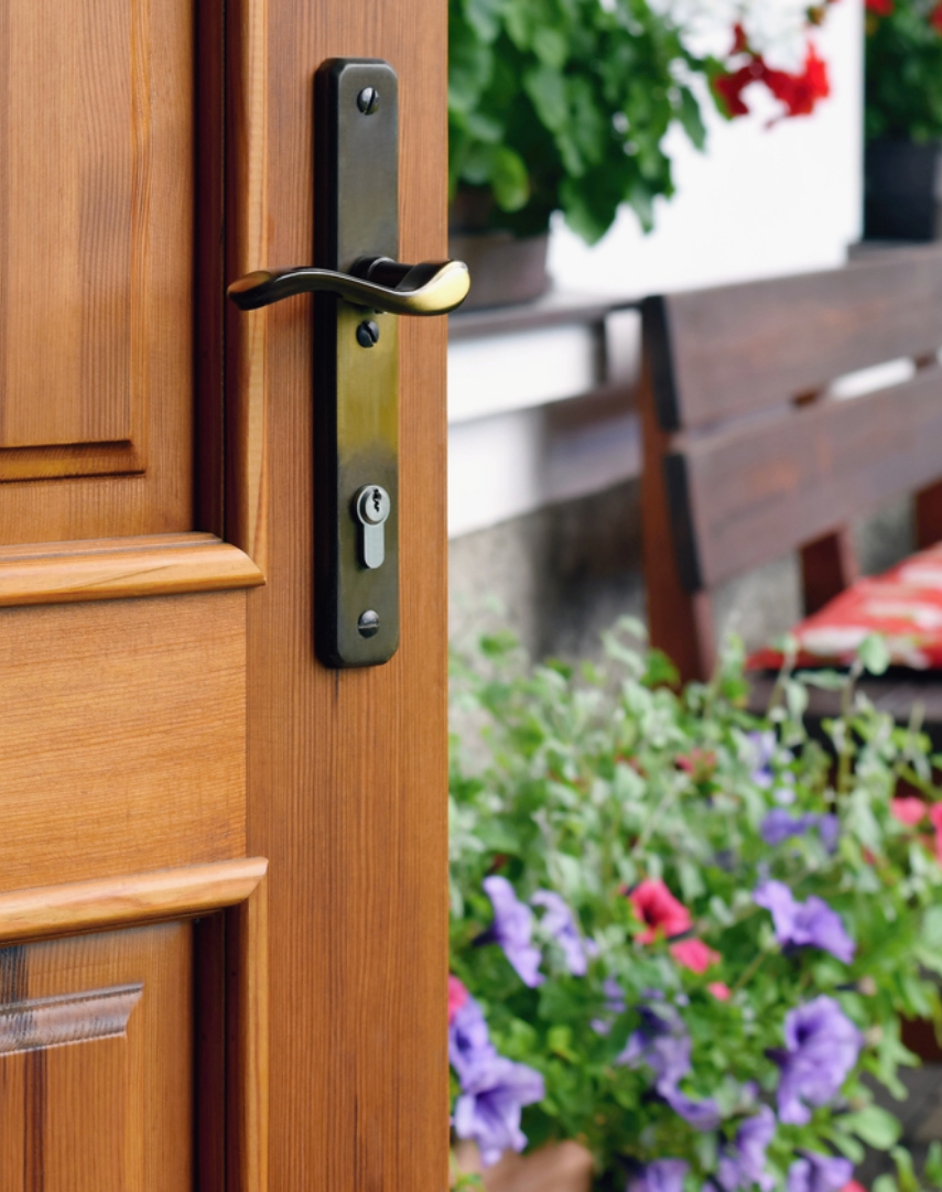 front door open with flowers and bench